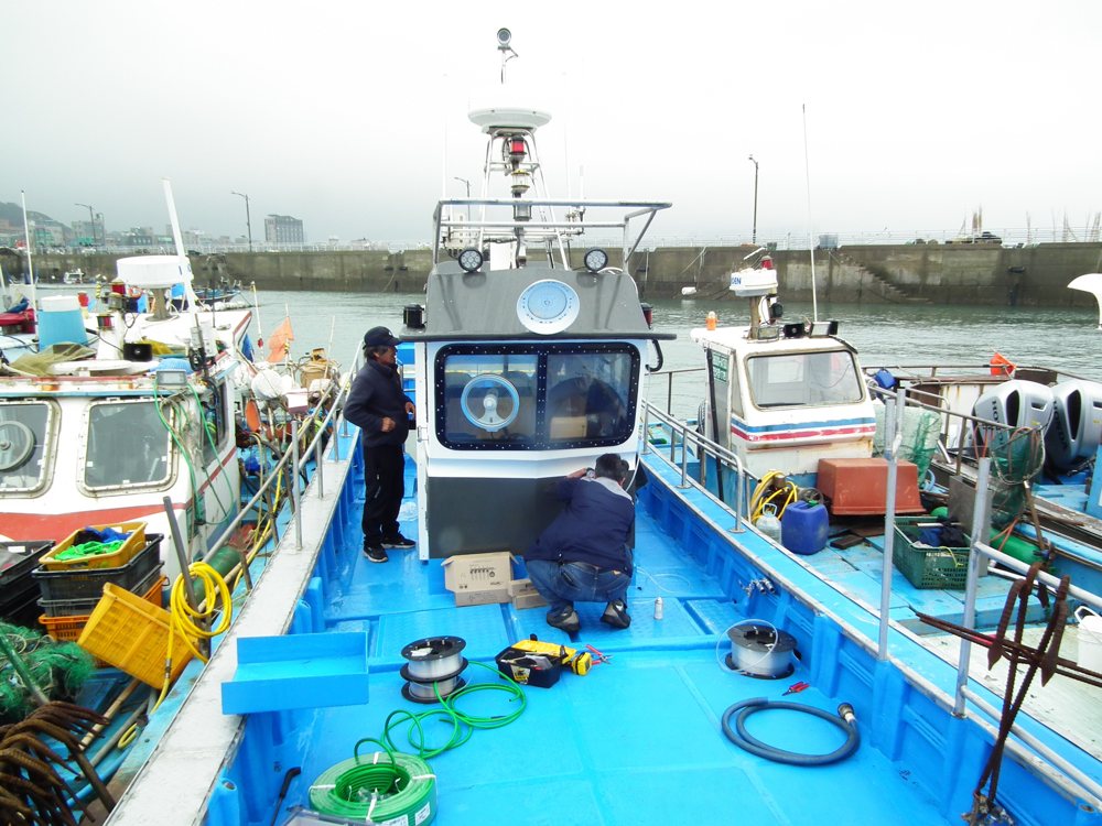 Technicians installing an O2MOS oxygen system on a small fishing vessel at the harbor